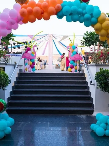 We love bringing fun themes to life. This colorful flamingo-themed party entrance uses a vibrant balloon arch over a staircase, with pink flamingo props nestled in clusters of teal balloons to welcome guests.