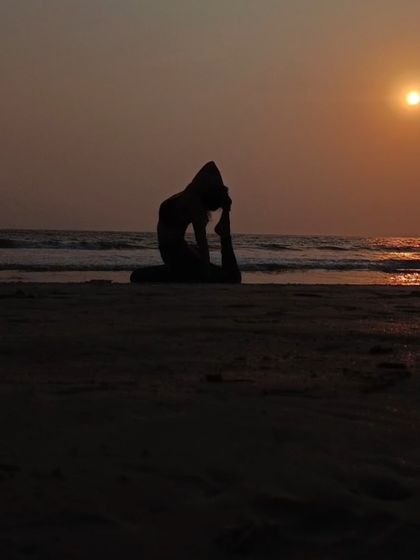 A silhouette of a one-legged king pigeon pose against the setting sun. Practicing on the beach as the day ends is a truly magical experience.