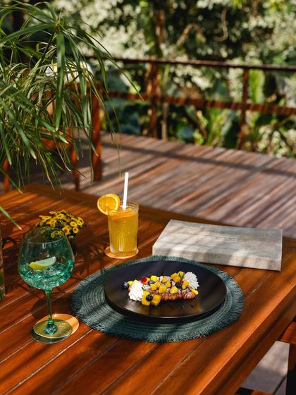 Brunch served on the deck, with dappled light filtering through the leaves. This dish features a croissant topped with fresh mango and blueberries.