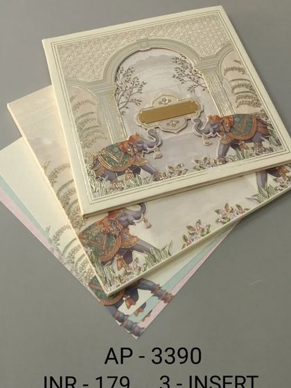 This cream-colored invitation features two caparisoned elephants under a traditional archway. The subtle texture and three-insert design make it a versatile choice for a classic Indian wedding.