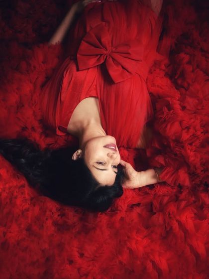 A creative overhead shot, where the mom-to-be is enveloped in a sea of red tulle. This artistic angle offers a unique and stunning perspective.