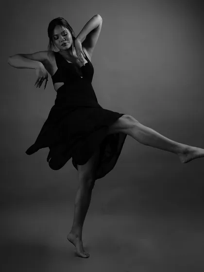 This dynamic pose captures a moment of powerful expression. In black and white, the focus shifts to the model's form, the flow of the dress, and the raw energy of the dance.