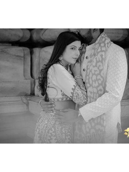 A classic black and white portrait that emphasizes emotion and texture. The focus is purely on the couple's embrace and the intricate details of their traditional attire.