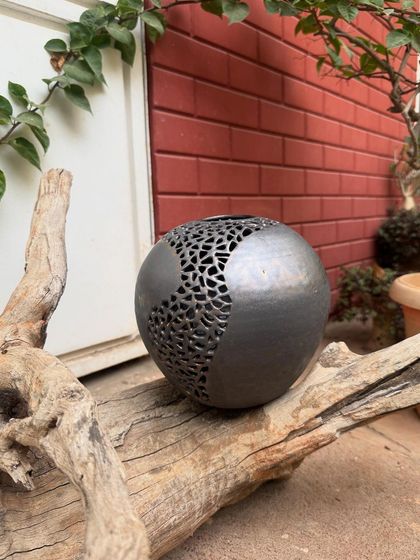 This wheel-thrown stoneware sphere features an intricate, hand-carved geometric pattern. I added a touch of gold to the metallic glaze to highlight the cuts and create a sense of depth.