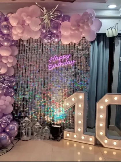 A 10th birthday party with a purple and silver balloon arch, a sequin wall, and "10" marquee numbers.