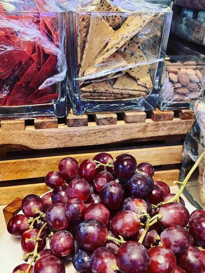 A rustic and charming grazing setup for a baby shower, featuring fresh grapes, assorted crackers, and nuts, ready for guests to enjoy.
