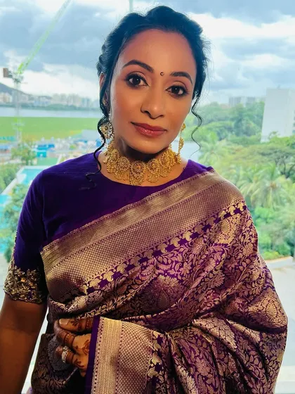 A soft glam look with a braided bun for this beautiful client. The makeup is elegant and timeless, perfectly complementing her traditional purple silk saree.