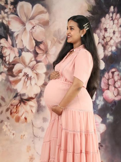 A stunning side profile of a mom-to-be against a floral backdrop. This shot beautifully captures her glowing smile and the roundness of her baby bump.