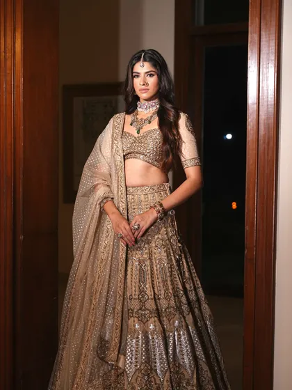 A classic portrait in a doorway. The styling of this golden lehenga is designed to look elegant and sophisticated in any setting.