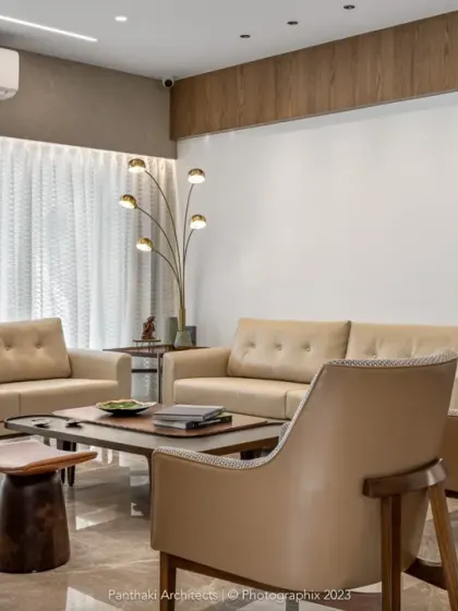A living room designed for comfort and relaxation. The neutral color palette of the sofas and chairs, combined with soft lighting and sheer curtains, creates a serene and welcoming environment.