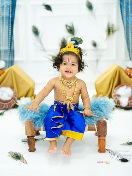 The happiest little Krishna, sitting on his cot and ready to play. His infectious smile and the vibrant blue costume make this a standout Janmashtami photo.