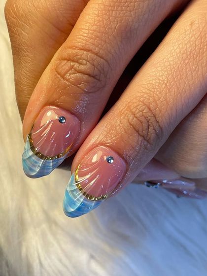 A close-up of our unique French tip design. We created a beautiful blue wave pattern on the tips and added a delicate gold chain and a single rhinestone for a touch of elegance.