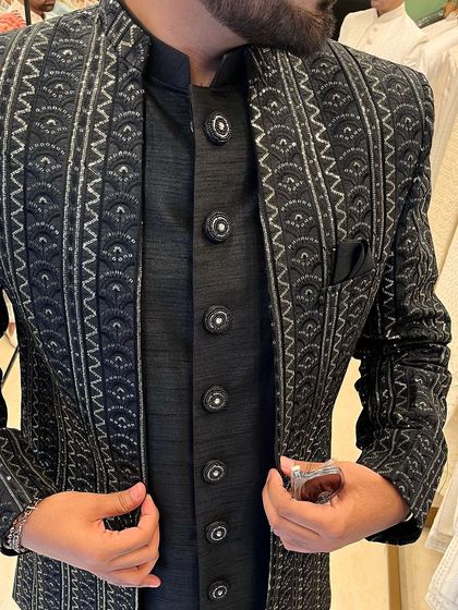 A close-up shot of the intricate silver embroidery and custom buttons on the black bandhgala jacket.
