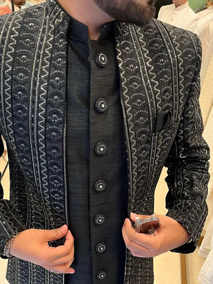 A close-up on the intricate details of the black and silver jacket, showing the quality of the embroidery and the stylish buttons.