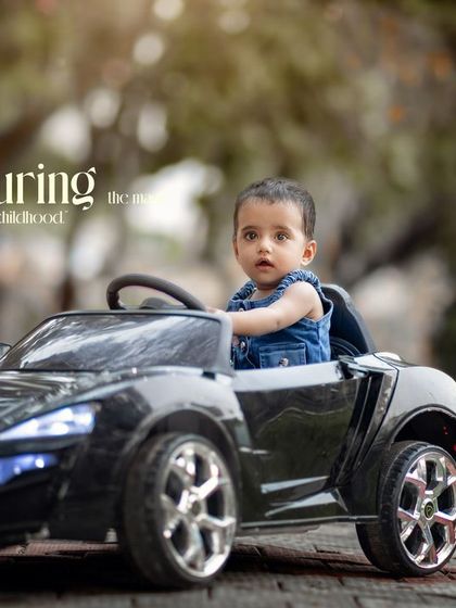 Capturing the magic of childhood. A serious-looking toddler takes the wheel, ready for his driving adventure.