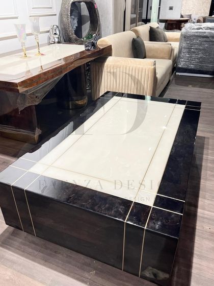 This center table combines a dark, high-gloss veneer with a central white onyx panel and delicate brass inlay. The design is a perfect example of modern luxury, blending different materials for a sophisticated result.