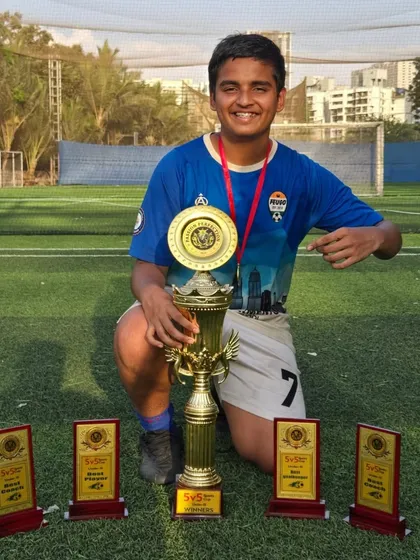 This U15 player proudly points to his team's championship trophy.