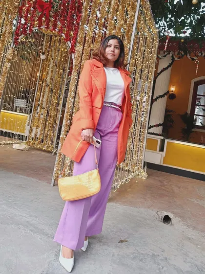 This full-length shot shows how the color-blocked outfit comes together. The bright coat and pants make a statement, while the neutral white shoes and simple bag keep the look balanced.