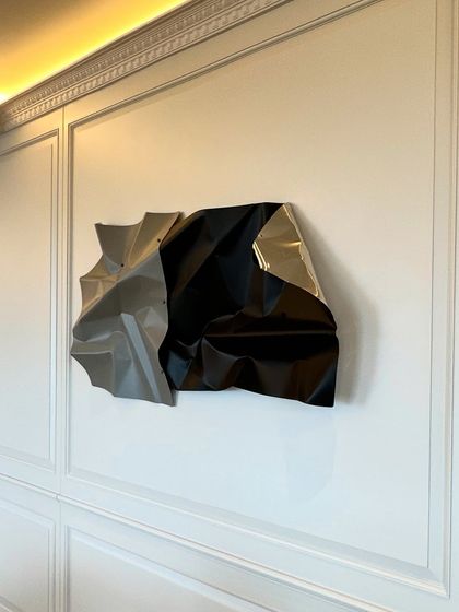 A close-up of the black and grey sculpture against the classic wall molding.