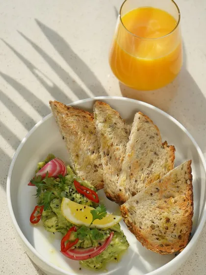 Our signature Smashed Chilli & Avocado Toast, beautifully plated with fresh orange juice. The vibrant colors and fresh ingredients make this a perfect all-day brunch dish.