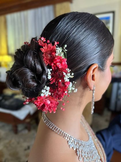 This intricate bridal bun is styled with a mix of red and white flowers, creating a beautiful contrast. It's a classic choice for a wedding ceremony look.