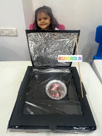 Peeking into her DIY solar oven to check on the progress. This project is a fantastic way to teach kids about renewable energy in a tangible and exciting way.