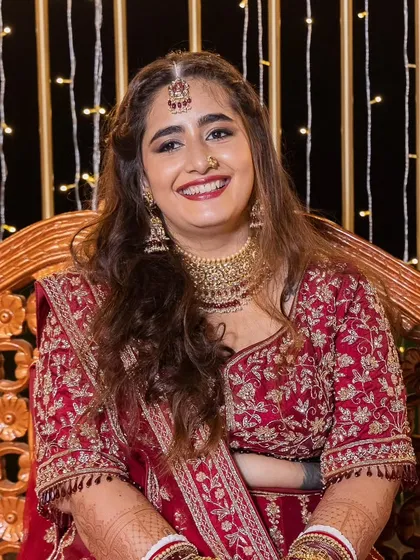 A video and photo series of this bride's reception look. She is glowing with happiness. Her makeup is glamorous with a bold red lip, and her hair is styled in soft waves, creating a stunning look for her celebration.