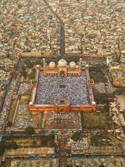 A high-altitude drone photograph of Jama Masjid, showing the mosque and the main road leading to it, filled with people.