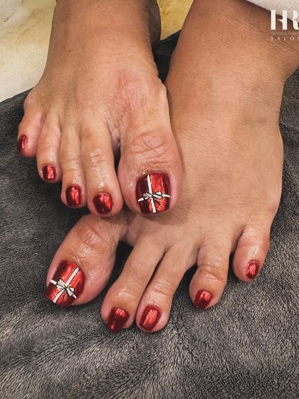 Don't forget your toes. We gave this client a festive pedicure with a stunning metallic red polish and a cute gift bow design on the big toe to match the holiday mood.