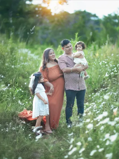 A candid moment of the family interacting in the wildflower field. The warm sunset light makes everything glow.