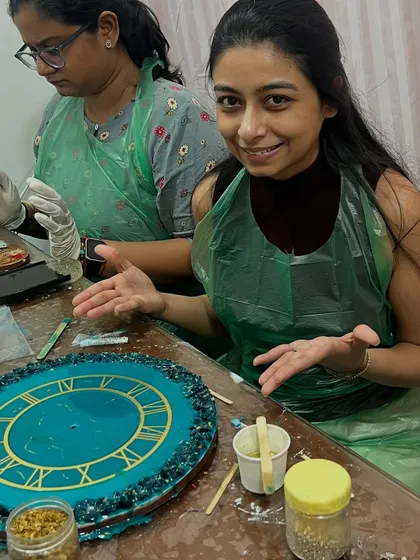 Here's a participant in the middle of creating her own resin wall clock. You can see the focus and fun involved as she prepares to pour the resin and add decorative elements. No prior art experience is needed to make something amazing.