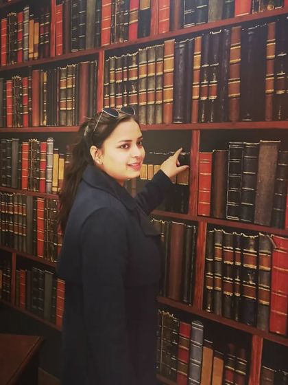 In a library, pointing to a book. This symbolizes my direct engagement with the source of law and knowledge, which is the foundation of my practice.