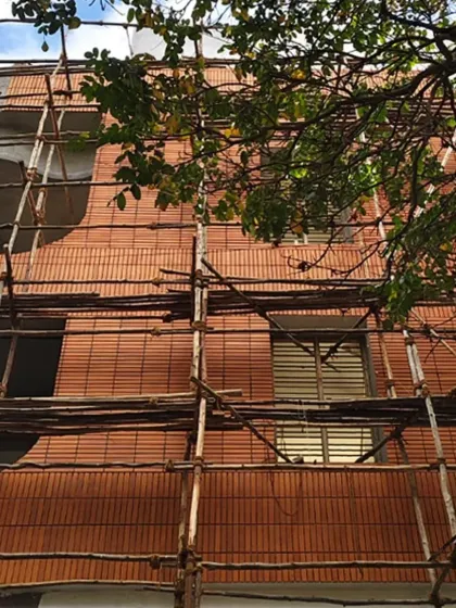 The curved brick facade of 'Kutumb' seen through the trees, showing how the building begins to settle into its environment.