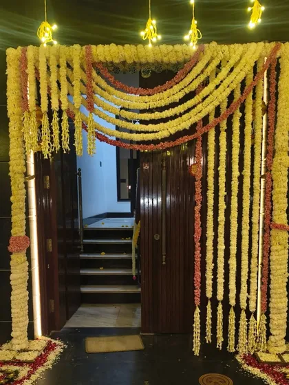 An entrance gate decorated for Diwali with traditional garlands of jasmine (mogra) and roses, illuminated by small lights.