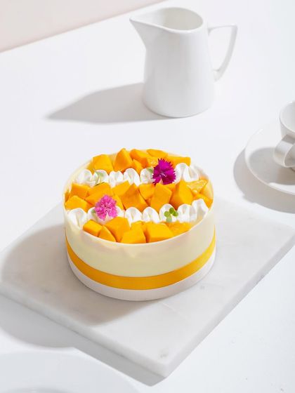 Our elegant mango cake, decorated with fresh mango and edible flowers.