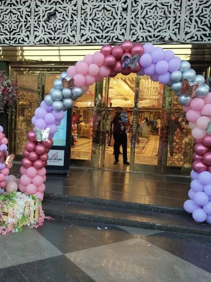 The entrance decor for the party, featuring a welcome sign and a beautiful balloon arch in shades of pink, purple, and silver.