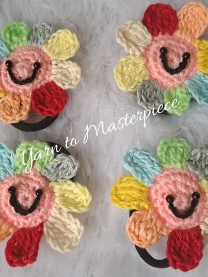 Add a pop of color with these cheerful rainbow flower hair ties. Inspired by the famous Takashi Murakami flower, these smiling accessories are made with soft cotton yarn and are perfect for brightening up any hairstyle.