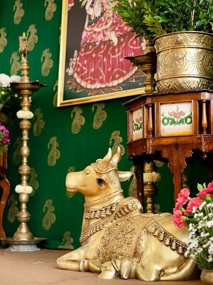 A closer look at the traditional setup with a seated brass Nandi, antique furniture, and a backdrop with a classic Indian painting.