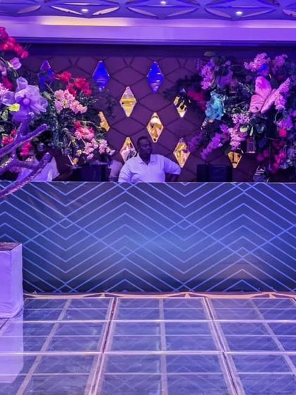 The DJ booth was framed by an explosion of colorful flowers and a modern, geometric-patterned console, ensuring the music hub was as visually exciting as the dance floor.