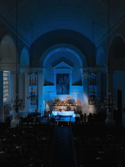A wide shot showing the serene blue lighting that filled the venue during the meditative portion of the evening. The goal is to create a complete sensory experience that promotes calm.