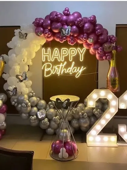 A stylish 23rd birthday setup with a circular balloon arch, a 'Happy Birthday' neon sign, and a '23' marquee light.