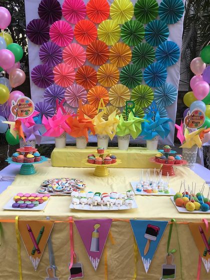 The dessert table at the art party, featuring a rainbow pinwheel backdrop and treats arranged like a palette of edible colors.