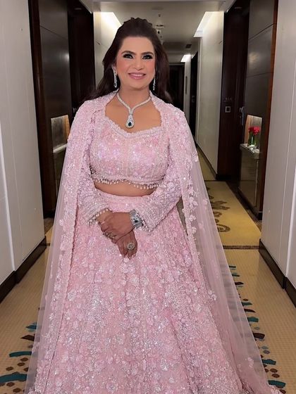 A full-length portrait of the groom's mother. She looks absolutely regal in her sequined pink lehenga, with makeup that enhances her grace.