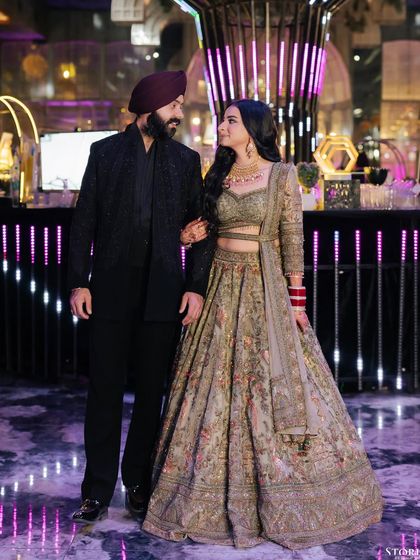 A full-length portrait of the couple at their reception, showcasing their elegant, coordinated outfits against a modern backdrop.