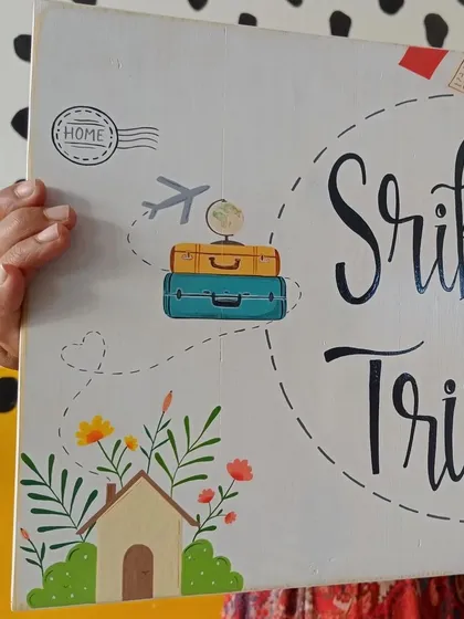 A close-up of the corner of the "Srikant and Trisha" board, detailing the little house and flowers that represent their new home together.