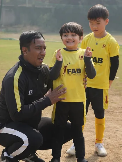 A coach celebrating with two young players. We prioritize holistic development, nurturing both athletic skills and personal growth.