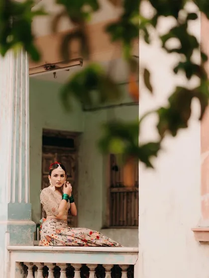 A beautifully composed shot of a bride during a quiet moment. We styled her in a floral lehenga with contrasting green bangles, a perfect look for a daytime event like a Mehendi or Roka ceremony.