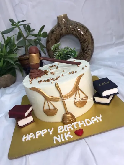 A simple yet elegant lawyer-themed cake with a gavel and books.