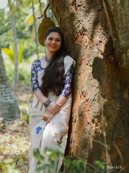 A happy and relaxed outdoor portrait in a saree, leaning against a tree. This shot feels natural and full of warmth.