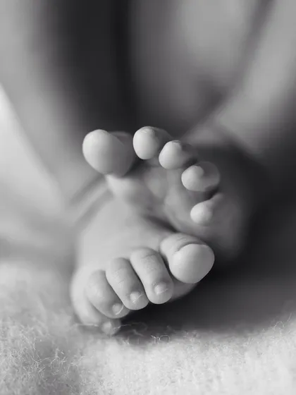 A macro shot of a newborn's crossed feet, showing every perfect little wrinkle and toe. These are the details that truly matter.